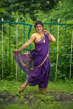 Beautiful Indian young girl in Traditional Saree posing outdoors