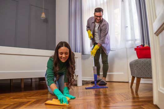 Young happy couple is cleaning their apartment.