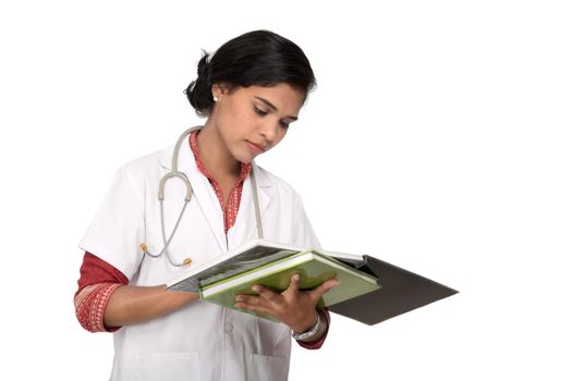 Young woman doctor with stethoscope is writing in book