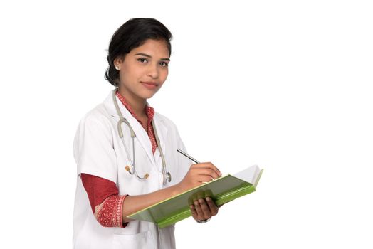 Young woman doctor with stethoscope is writing in book