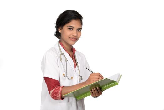 Young woman doctor with stethoscope is writing in book