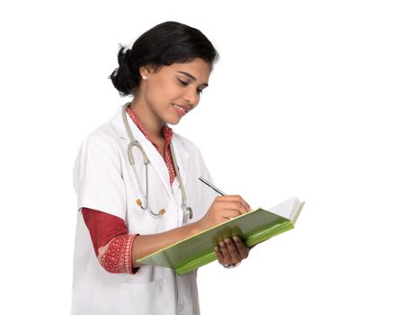 Young woman doctor with stethoscope is writing in book