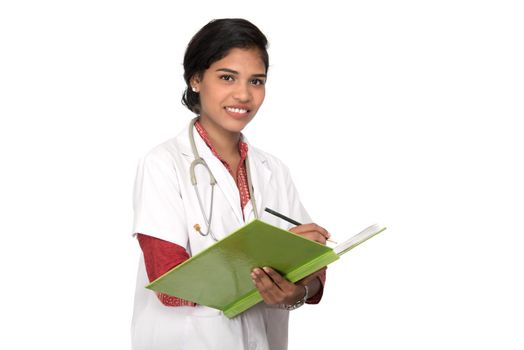 Young woman doctor with stethoscope is writing in book