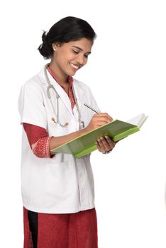 Young woman doctor with stethoscope is writing in book