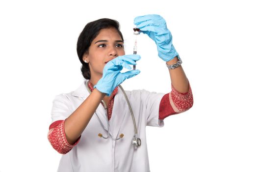 A female doctor with a stethoscope is holding an Injection or Syringe.