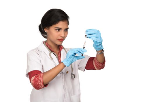 A female doctor with a stethoscope is holding an Injection or Syringe.