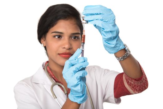 A female doctor with a stethoscope is holding an Injection or Syringe.