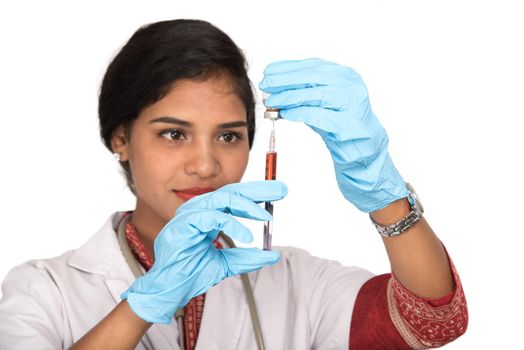 A female doctor with a stethoscope is holding an Injection or Syringe.