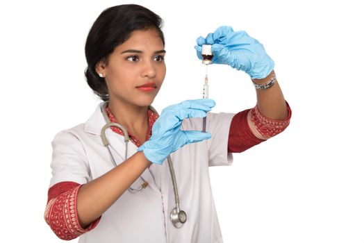 A female doctor with a stethoscope is holding an Injection or Syringe.