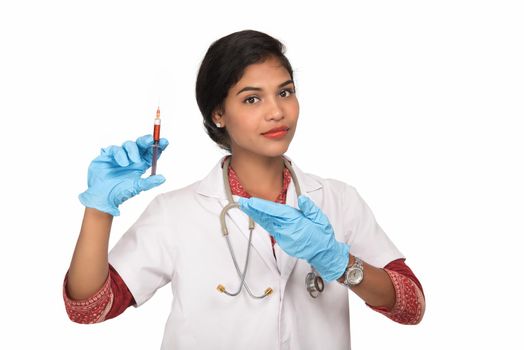 A female doctor with a stethoscope is holding an Injection or Syringe.