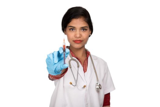 A female doctor with a stethoscope is holding an Injection or Syringe.