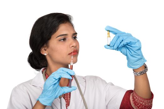 A female doctor with a stethoscope is holding an Injection or Syringe.