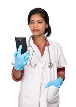 Female doctor with stethoscope talking on mobile phone on white background