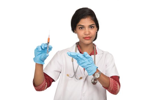 A female doctor with a stethoscope is holding an Injection or Syringe.