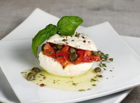 Mozzarella stuffed tomatoes with capers, seasoned   spices and basil in oil