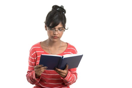 Pretty young girl holding book and posing on white background