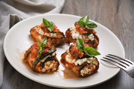 Baked zucchini rolls stuffed with ricotta and basil under tomato-onion-carrot gravy 