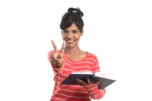 Pretty young girl holding book and posing on white background