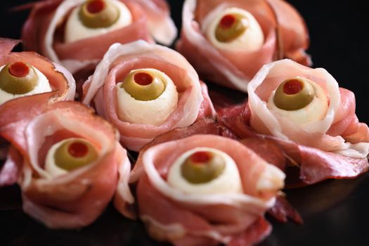 Original Halloween snacks. Eyeballs cooked from  jamon with mozzarella, olives stuffed with red pepper