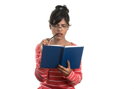 Pretty young girl holding book and posing on white background