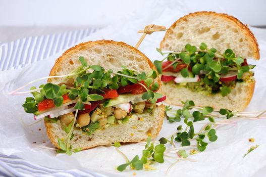 Sandwich with green radish sprouts crispy radish and cucumber, tomato with avocado dressing and mustard with herbs.