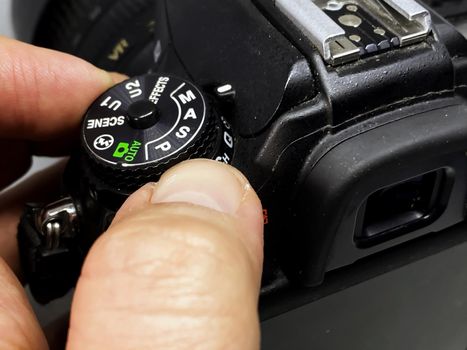 photographer turning the cogwheel to select the correct camera setting to take a picture. Buttons and settings of a digital DSLR camera.