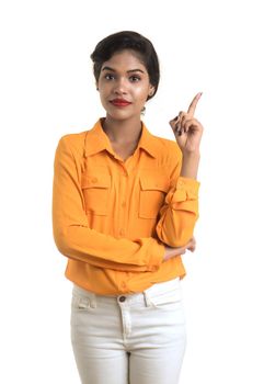 Young smiling girl pointing fingers to copy space on a white background