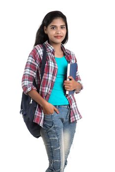 young Indian woman with backpack standing and holding notebooks, posing on a white background.