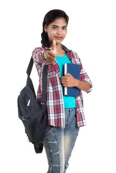 young Indian woman with backpack standing and holding notebooks, posing on a white background.