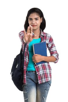 young Indian woman with backpack standing and holding notebooks, posing on a white background.