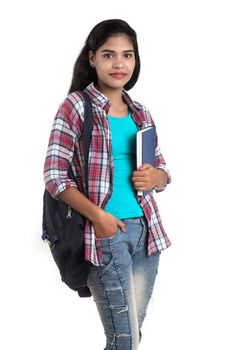 young Indian woman with backpack standing and holding notebooks, posing on a white background.