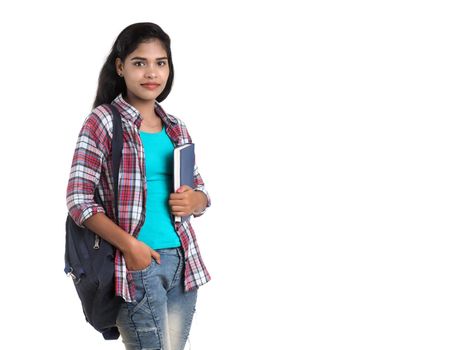 young Indian woman with backpack standing and holding notebooks, posing on a white background.