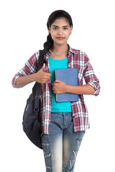 young Indian woman with backpack standing and holding notebooks, posing on a white background.