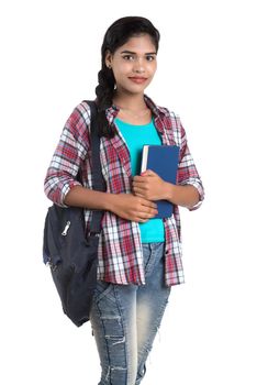 young Indian woman with backpack standing and holding notebooks, posing on a white background.