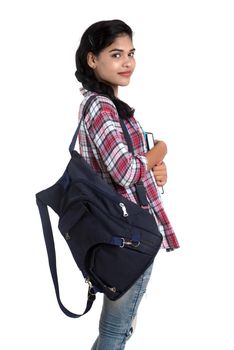 young Indian woman with backpack standing and holding notebooks, posing on a white background.