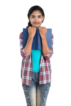 young Indian woman with backpack standing and holding notebooks, posing on a white background.