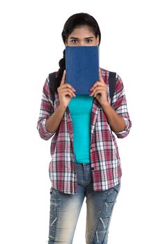 young Indian woman with backpack standing and holding notebooks, posing on a white background.