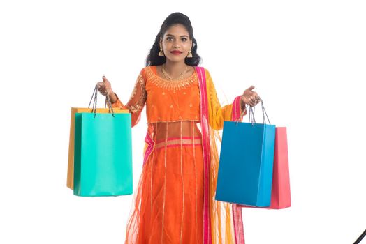 Beautiful Indian young girl holding shopping bags while wearing traditional ethnic wear. Isolated on a white background