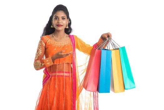 Beautiful Indian young girl holding shopping bags while wearing traditional ethnic wear. Isolated on a white background