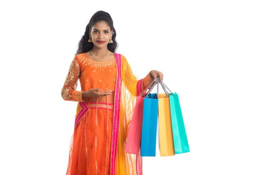 Beautiful Indian young girl holding shopping bags while wearing traditional ethnic wear. Isolated on a white background