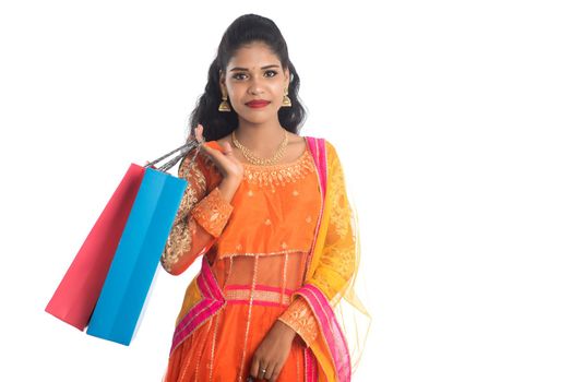 Beautiful Indian young girl holding shopping bags while wearing traditional ethnic wear. Isolated on a white background