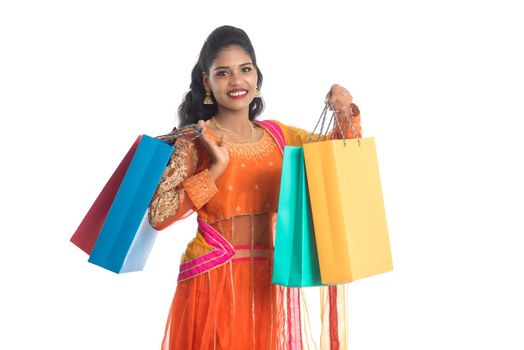 Beautiful Indian young girl holding shopping bags while wearing traditional ethnic wear. Isolated on a white background