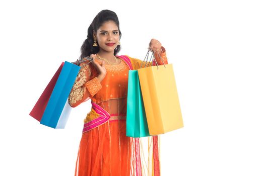 Beautiful Indian young girl holding shopping bags while wearing traditional ethnic wear. Isolated on a white background