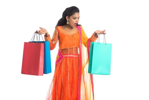 Beautiful Indian young girl holding shopping bags while wearing traditional ethnic wear. Isolated on a white background