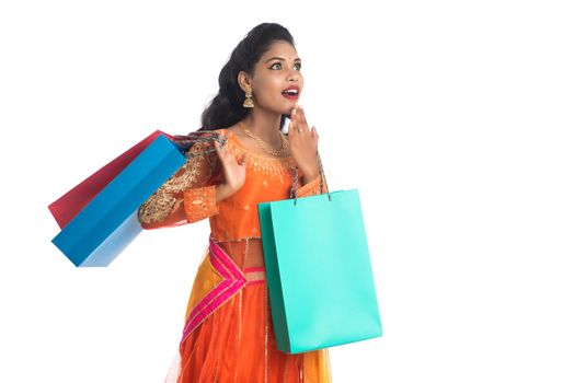 Beautiful Indian young girl holding shopping bags while wearing traditional ethnic wear. Isolated on a white background