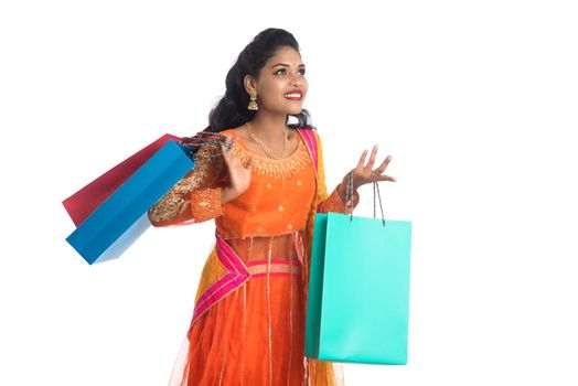 Beautiful Indian young girl holding shopping bags while wearing traditional ethnic wear. Isolated on a white background