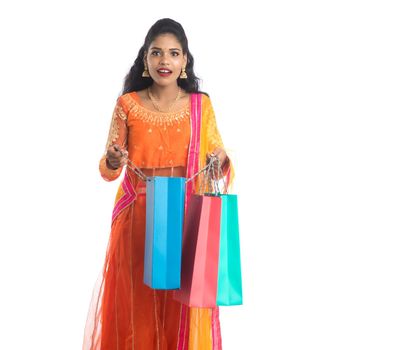 Beautiful Indian young girl holding shopping bags while wearing traditional ethnic wear. Isolated on a white background