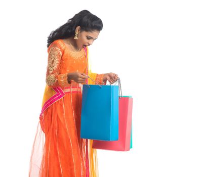 Beautiful Indian young girl holding shopping bags while wearing traditional ethnic wear. Isolated on a white background