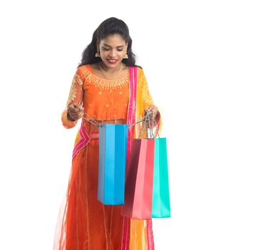 Beautiful Indian young girl holding shopping bags while wearing traditional ethnic wear. Isolated on a white background