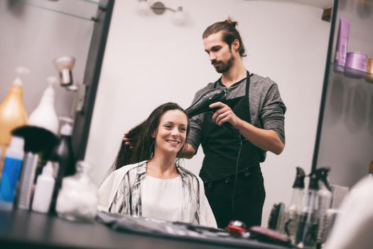 Young woman getting new hairstyle at professional hair styling saloon.